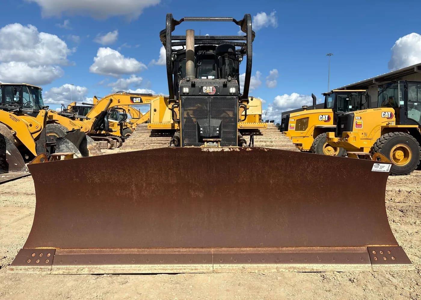 Dozer blade in the foreground with a line of further machines behind it